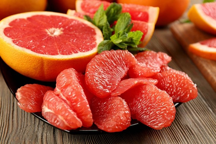 Juicy grapefruit pieces with fresh mint in a bowl, close up