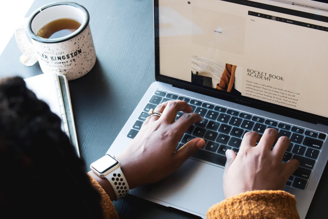 A woman\'s hands typing on a laptop keyboard