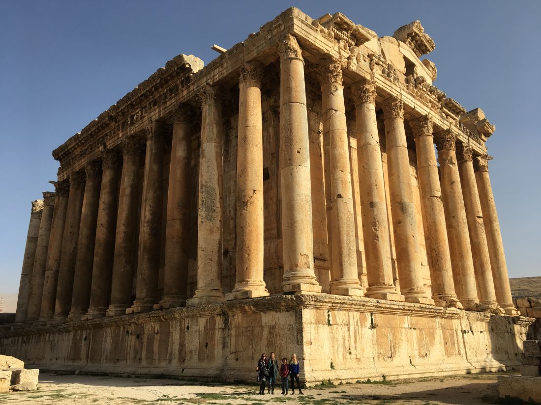 A full-scale view of an ancient building with a family posing in front and looking very small