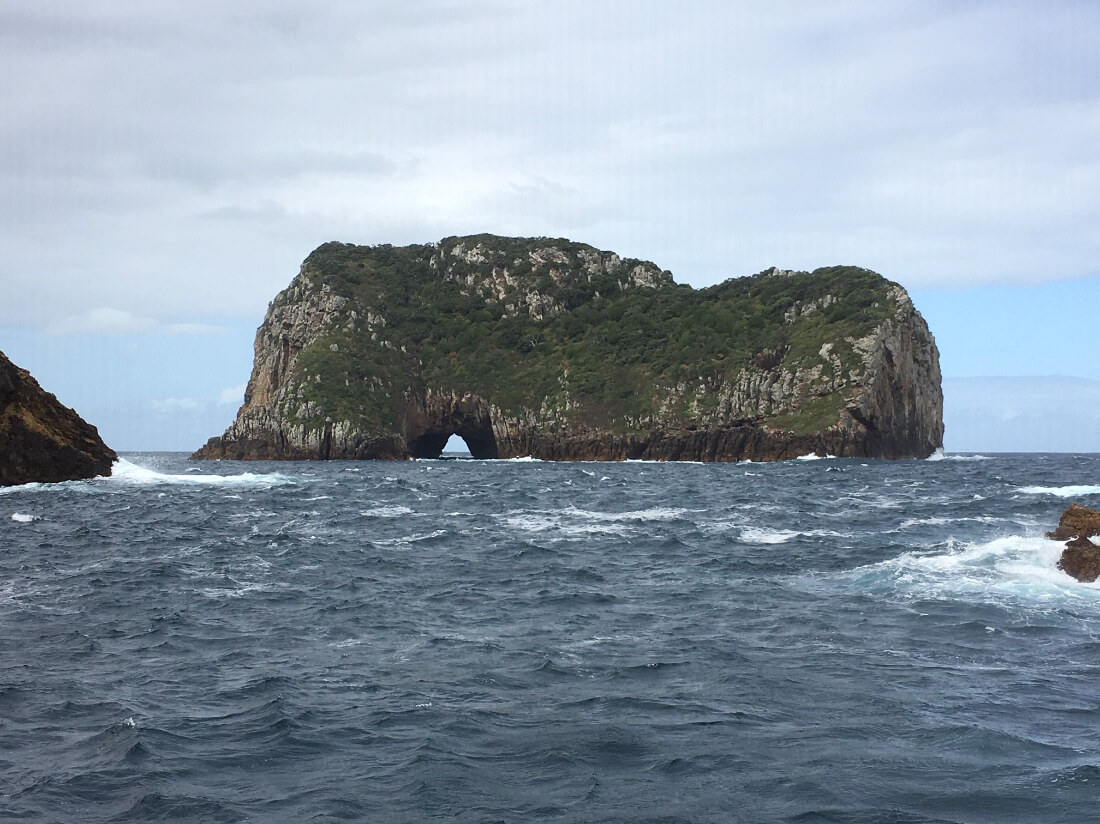 A photo taken at sea level looking at a small island rising up